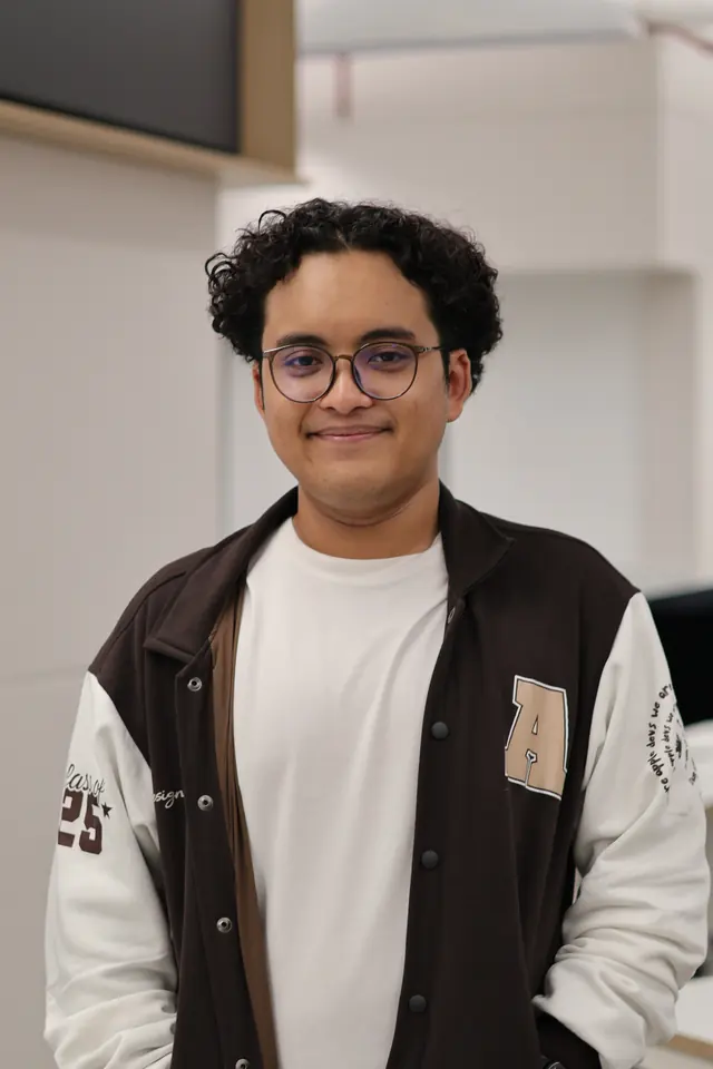 Adrian Rachman, smiling, in a black and white varsity jacket