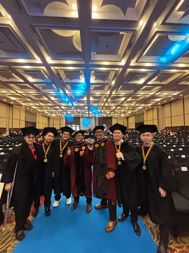 Graduates in black gowns and caps standing together in the ceremony hall