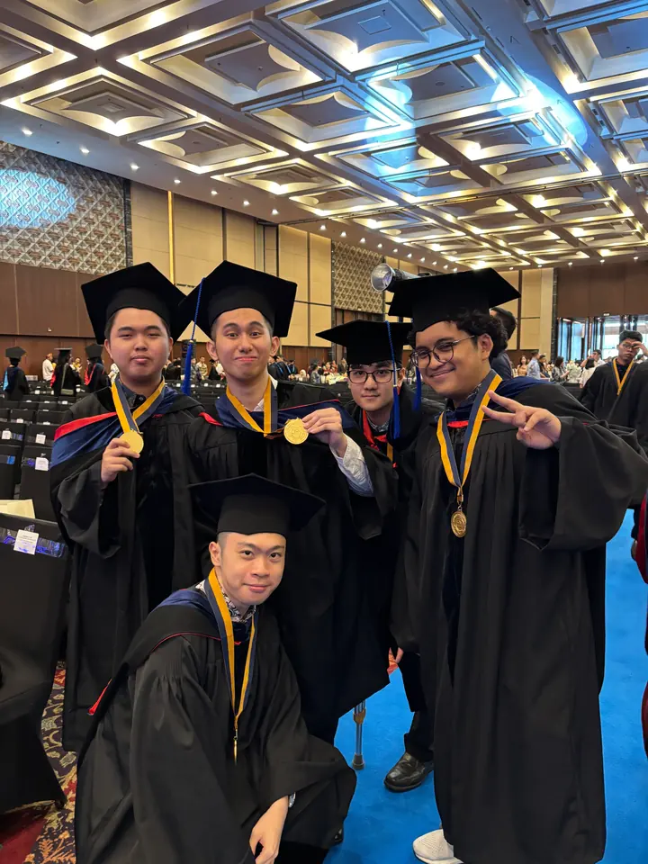 Adrian and friends in caps and gowns showing their medals