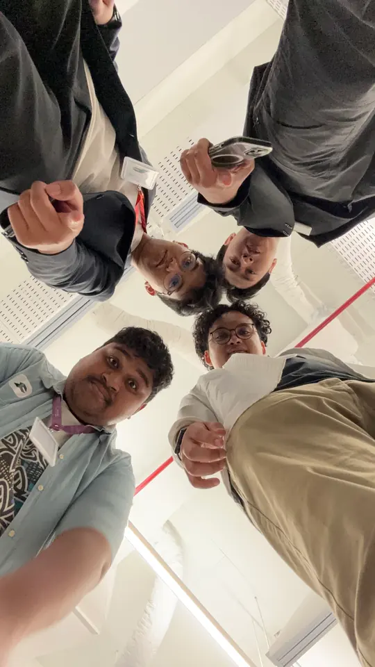The team leaning in over the camera in a circle, shot from below